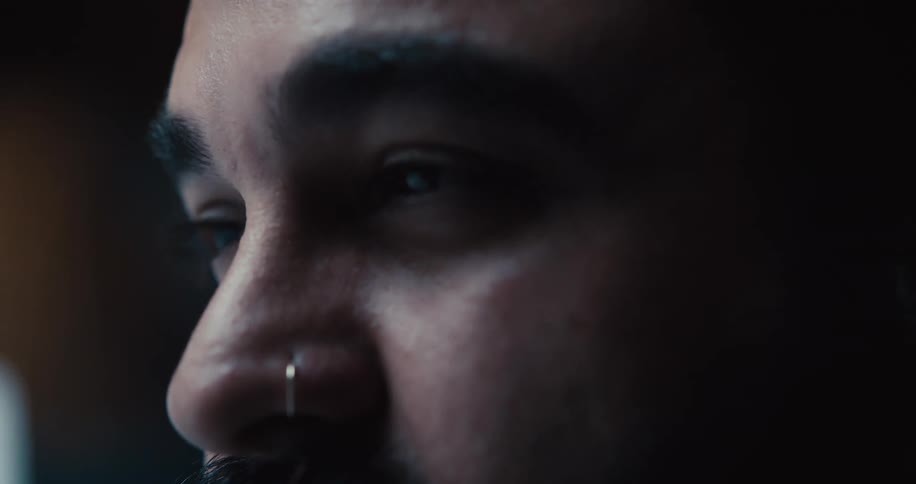 A partial shot of a black mans face as he is talking and shaking his head in a dimly lit room