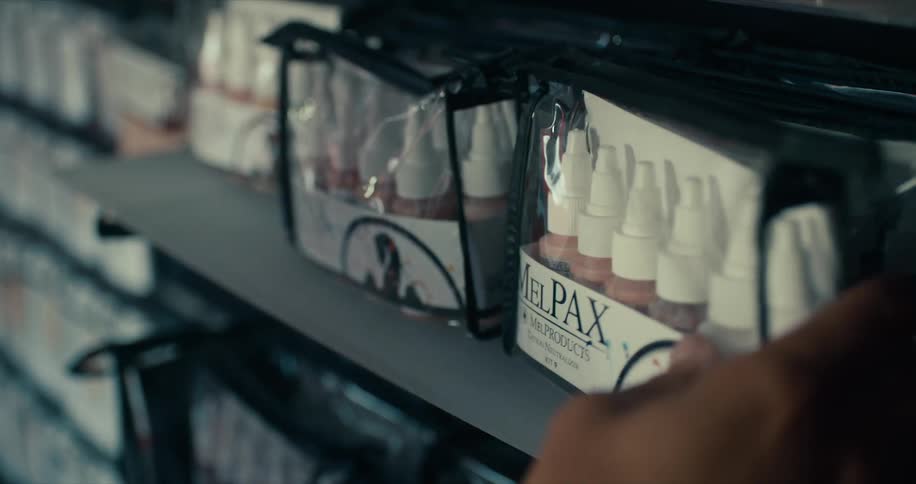 Packages of small bottles in different colors are placed on a shelf in a row