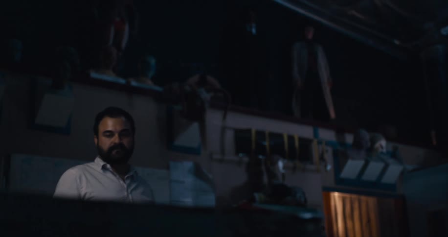 A man walks up to a table in his dark garage workshop