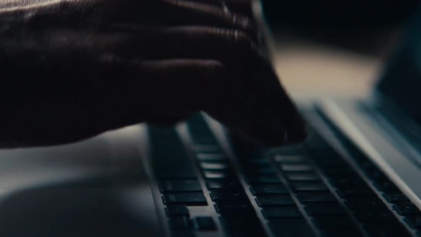 A pair of hands type on a laptop computer inside of a building