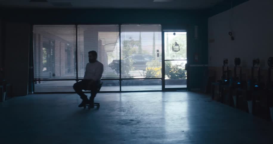 A man is sliding around on a chair operating film reels