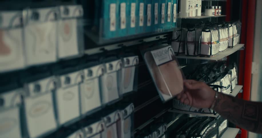Man stocks bald caps on shelf with other hair care items