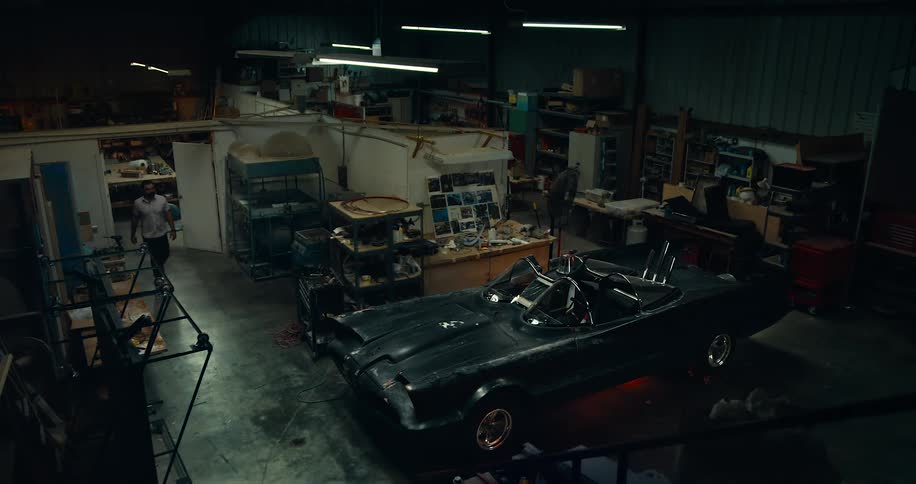 Man walking through garage to the car he is working on
