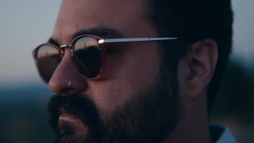 A man is standing outdoors while wearing sunglasses