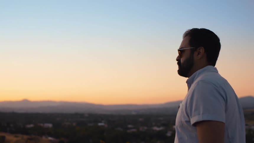 A man is standing outdoors at dusk