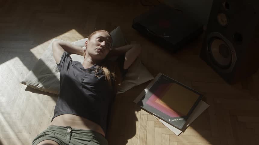 A woman lies on the floor next to vinyl records