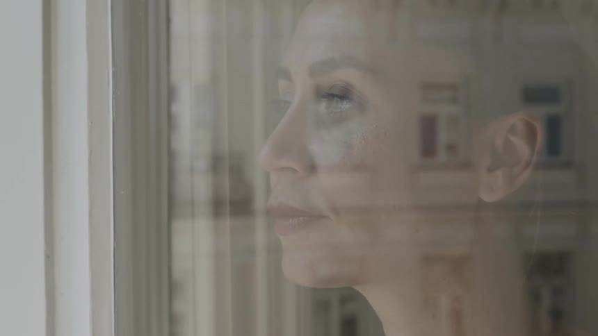 A woman is looking out a window during the day