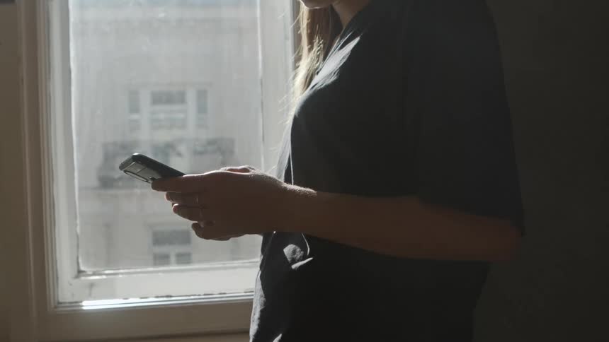 A woman is using her phone by the window