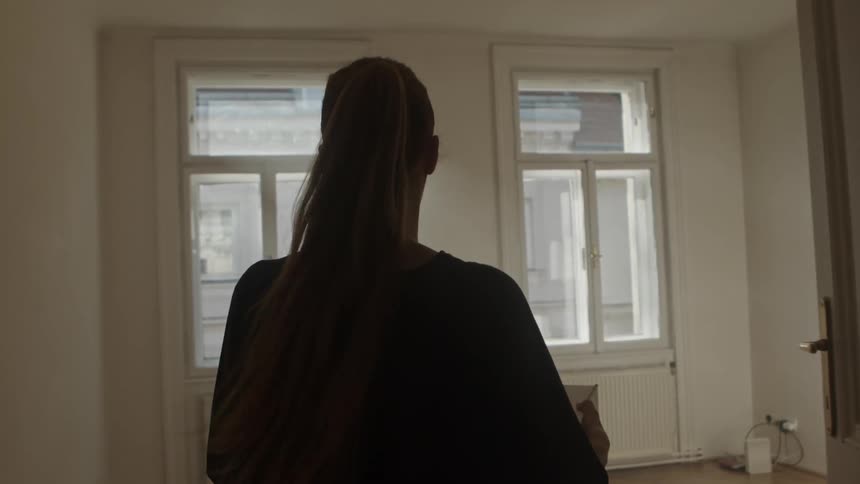 A woman carries a box in to an empty house