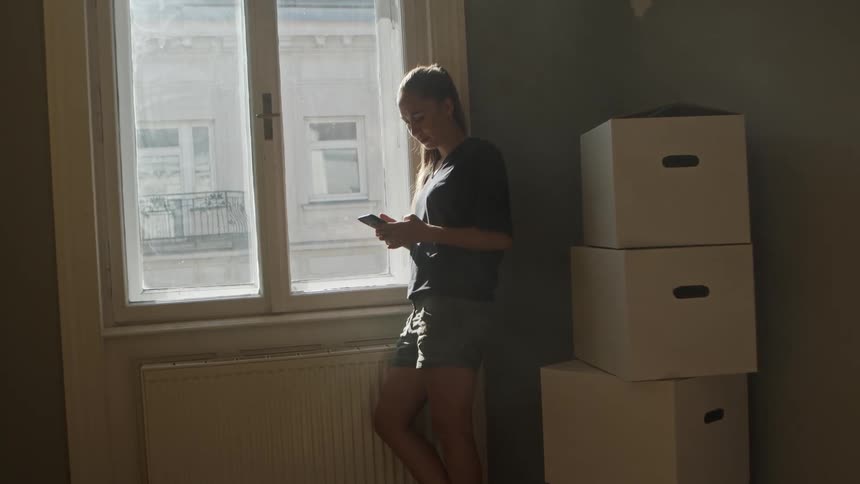 A woman is standing in a room next to a window