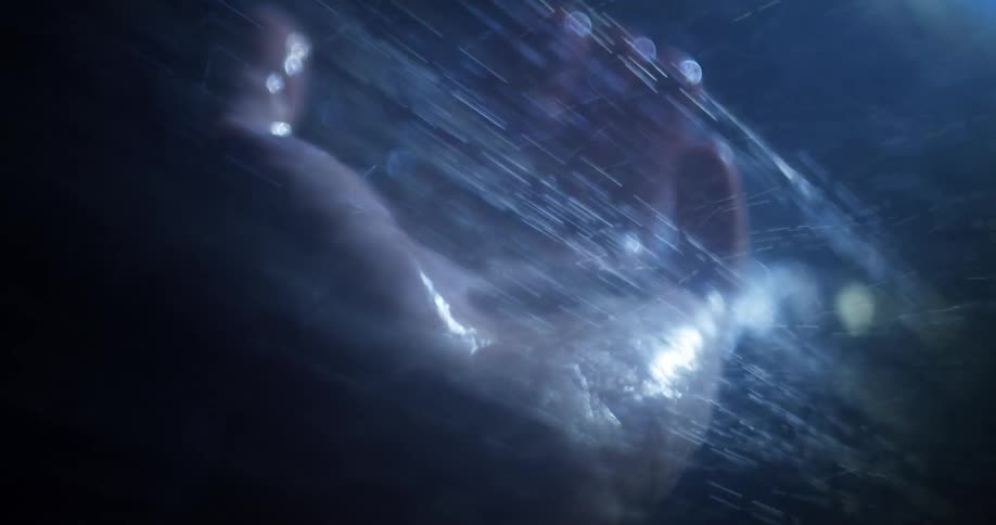 Rain falling on a persons hand as they open and close their fingers