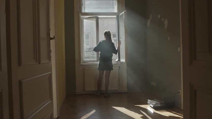 A woman is looking out a window during the day