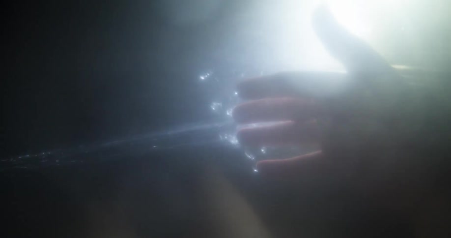 Water is streaming onto a hand with light behind the hand