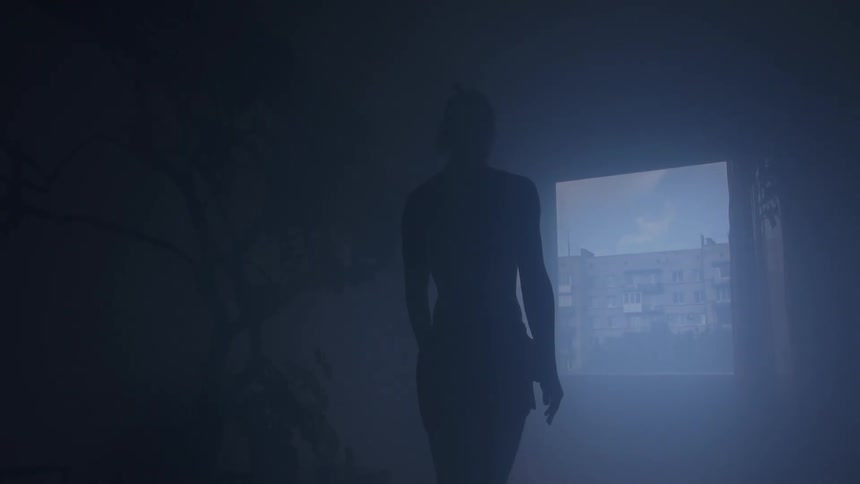 A female figure stands in a dark misty room while looking out of a window with a view of buildings
