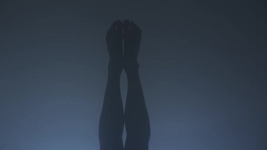 A pair of legs and feet are held close together with a murky grey background