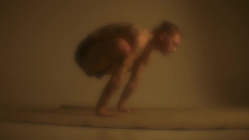 A man holds himself in a crow pose while doing yoga