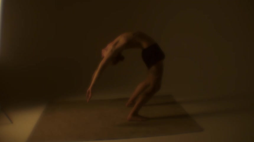 A man in a room standing and stretching on a mat