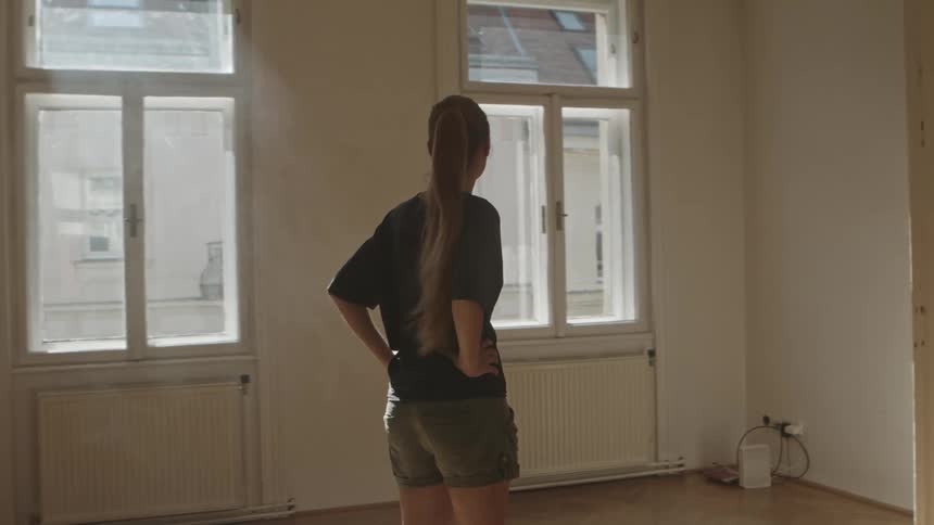 A woman is walking around an empty room
