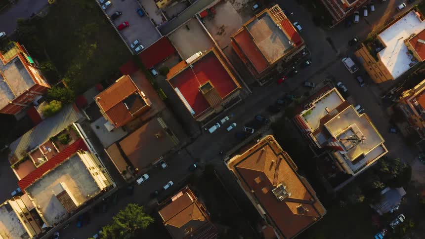 An aerial view of an urban neighborhood with a few cars parked and driving