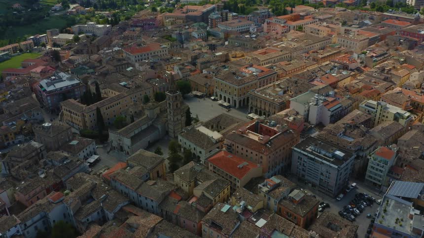 An old world town square with people walking in the mountains
