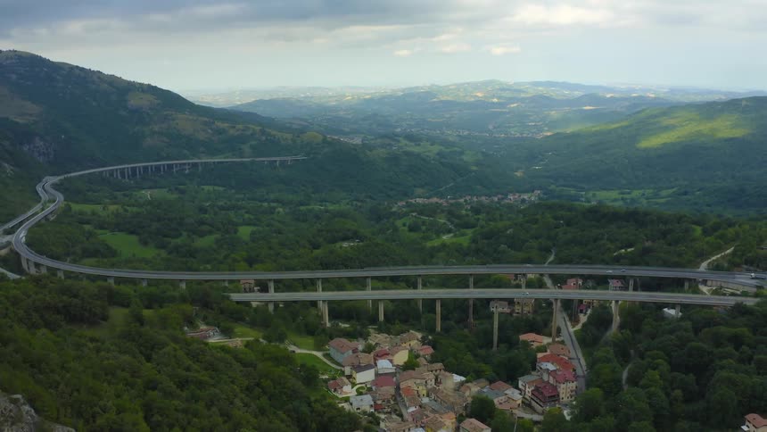 A winding freeway over a forest and small town in a mountain valley during the day