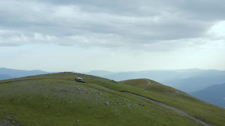 Mountains with car sitting at the top of a hill on a road
