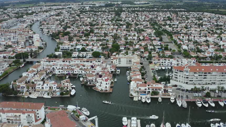 An aerial view of boats driving in a canal past hotels