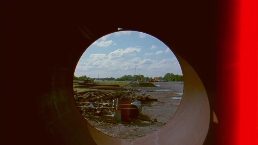 Garbage on the side of a neighborhood street seen from inside a tunnel