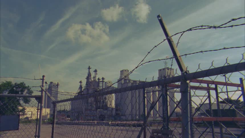 A camera tracks the exterior of a factory seemingly abandoned