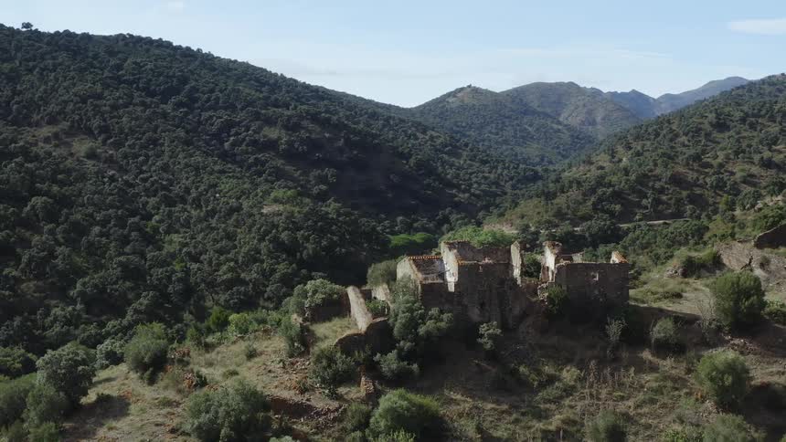 Structure in ruins on the top of a hill surrounded by other hills on a clear day