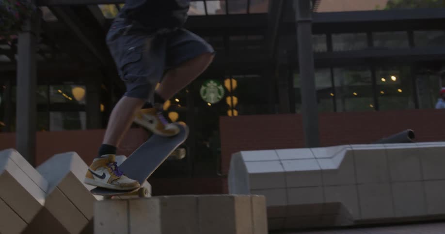 A boy skateboards in front of a building and completes jumps