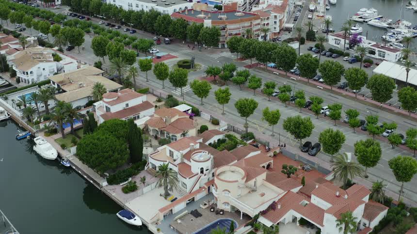 Homes on waterway with boats tree lined street and a large complex with a pool