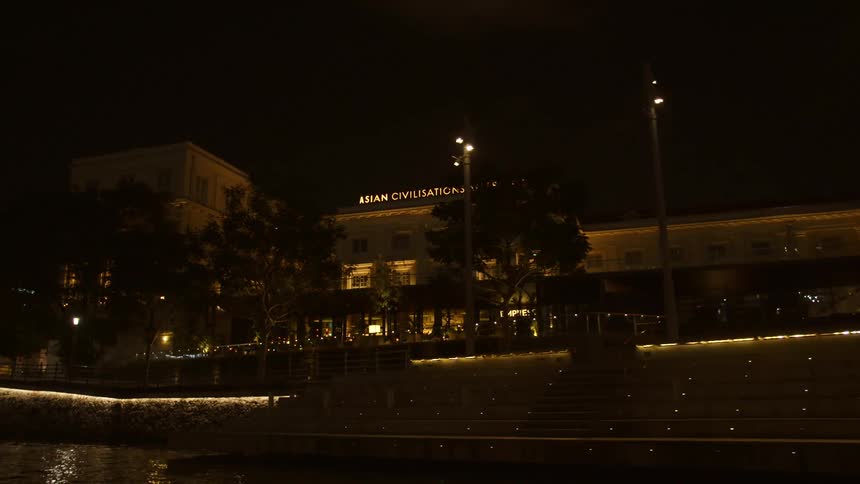 The illuminated exterior of a museum on the bank of a river at night