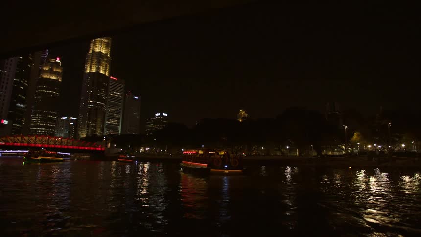 Ferries travel along a waterway in a metropolis at night