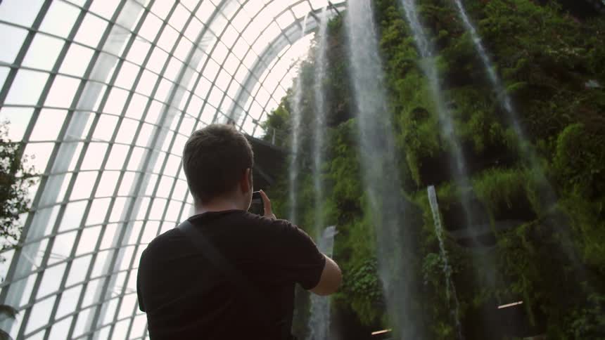 A man is photographing a rock formation that is spilling water