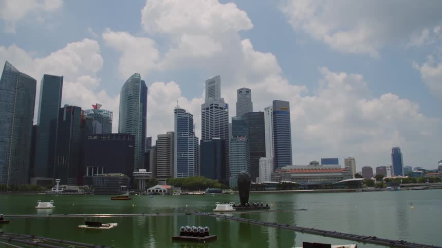 A city skyline with water in the foreground with boats on a sunny day