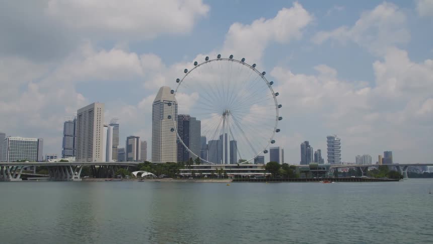 Ferris wheel stands at edge of city near waterfront