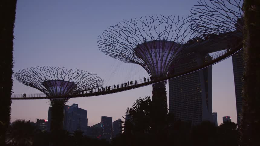 Pedestrians stand on a bridge surrounded by buildings and art pieces