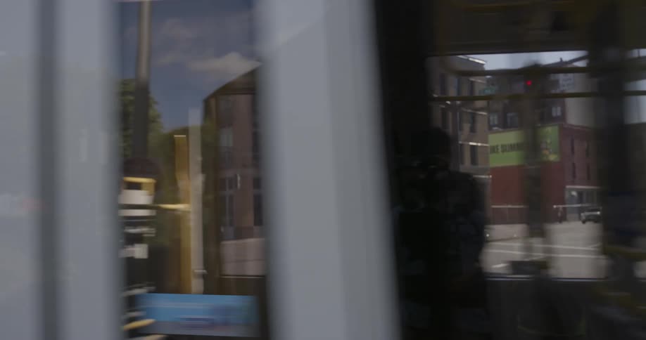 A train runs down a street in daylight with passengers