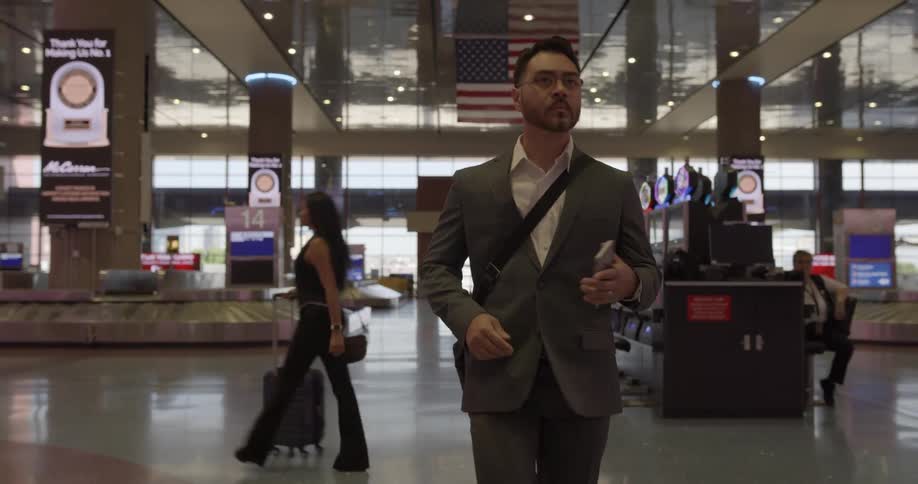 People walking through an airport terminal pulling suitcase and checking cell phones