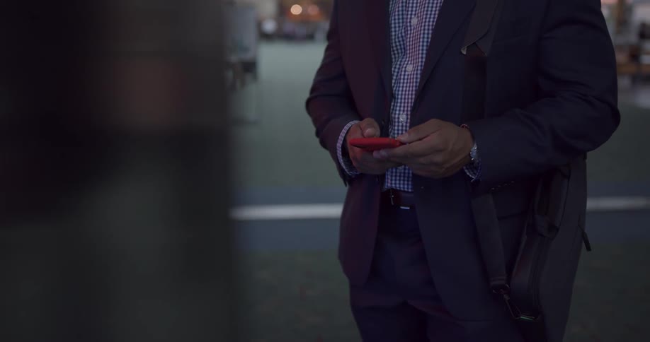 People walking around a terminal and a man takes out his phone and checks it