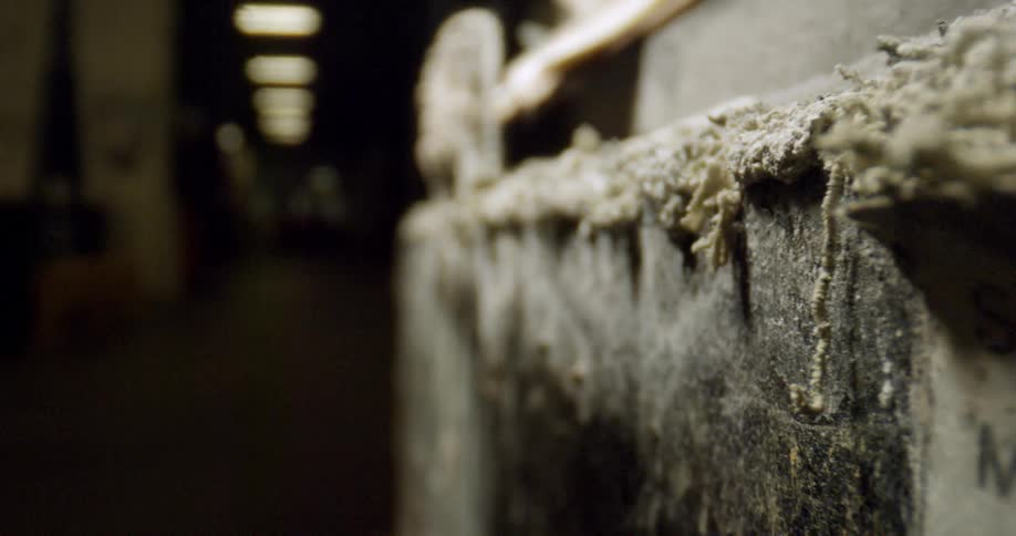 Light blinks at end of corridor in dark warehouse housing old labeled cartons showing stuffing