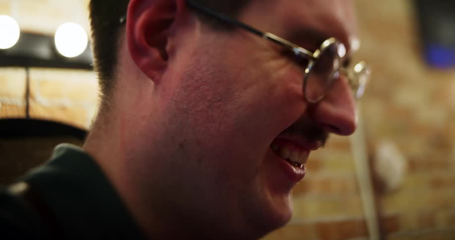A barber laughs as he cuts a mans hair