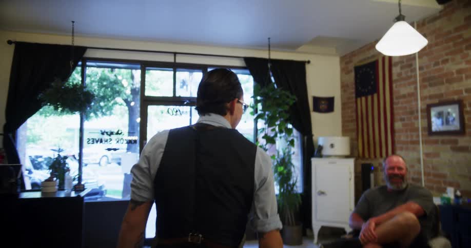 A man walking in a barbershop with a wall and a mirror in the background