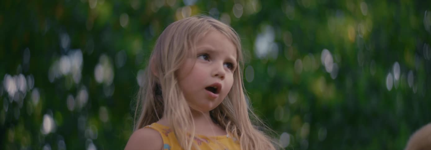 Blonde girl wearing yellow dress talks to someone
