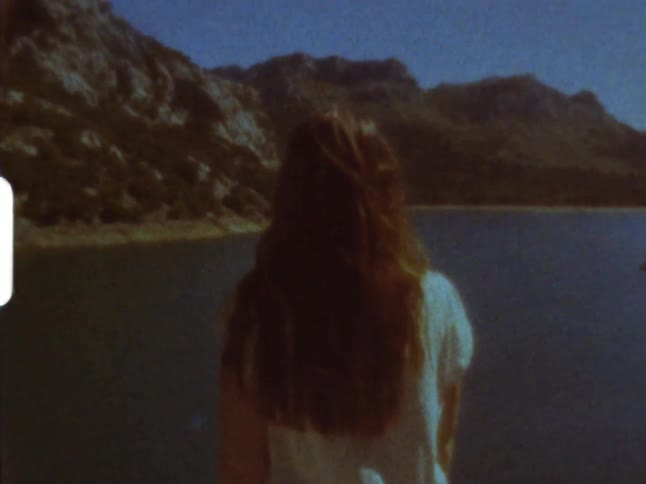 Long haired female looks at river between the mountains on 8mm