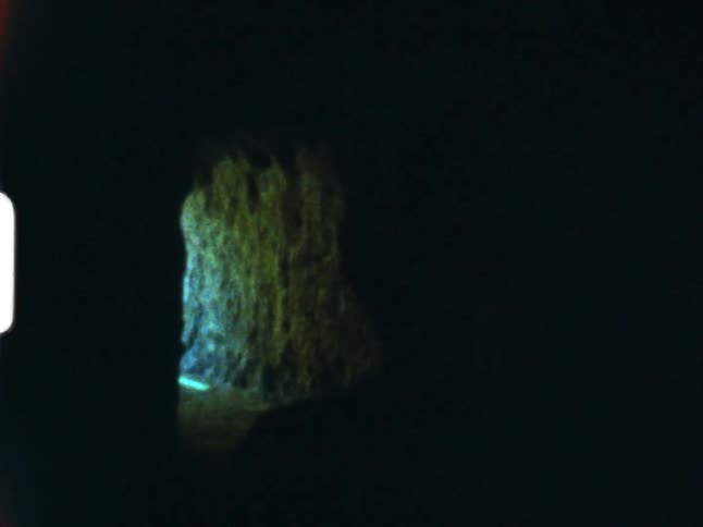 A woman waves through a cavern towards the entrance on 8mm