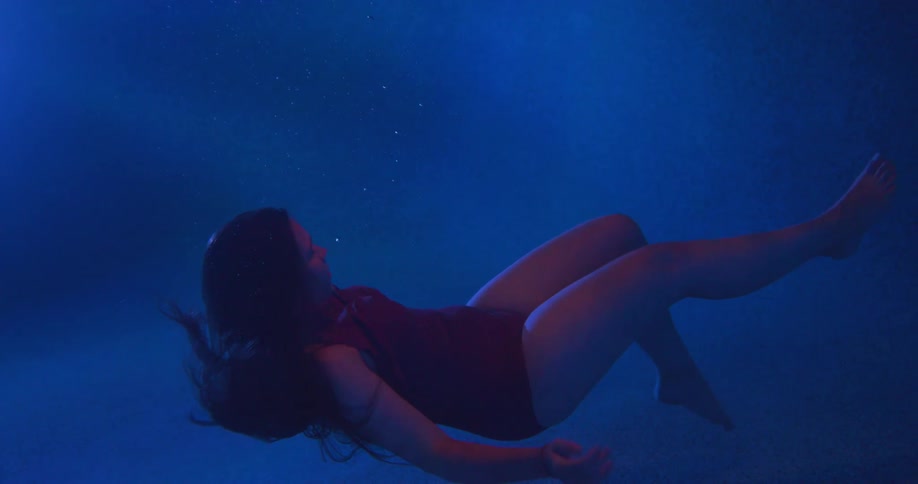 A woman with long brown hair suspended under blue water