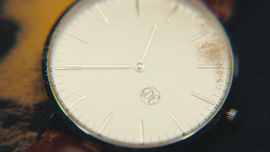Sand being blown off an analog wrist watch