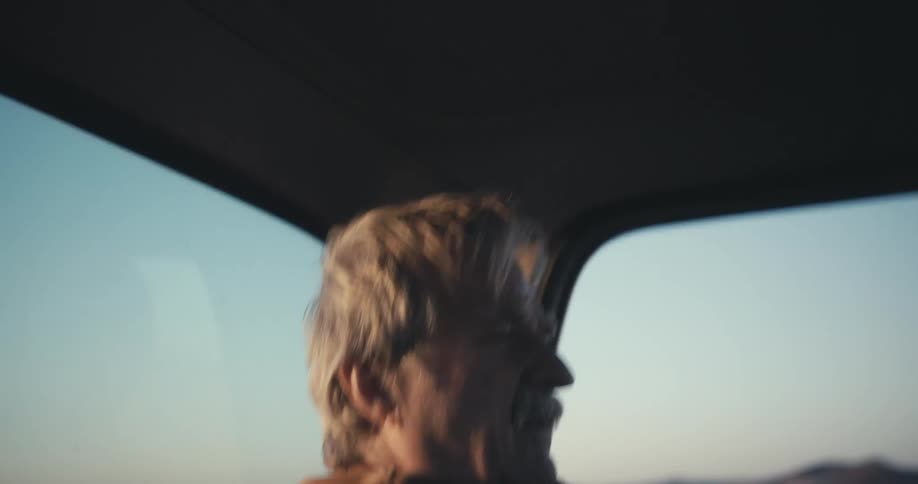 A man is driving a car at dusk